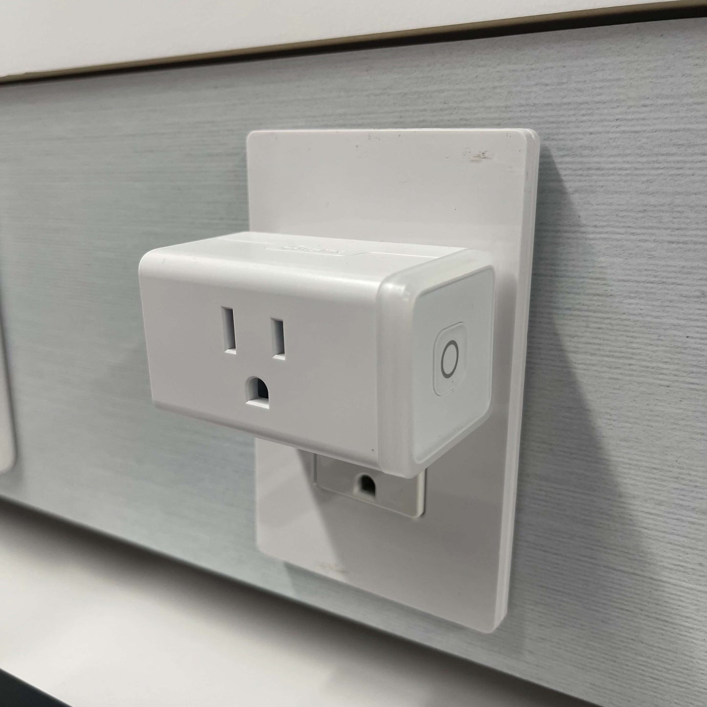 A smart plug installed into a wall outlet to control appliances connected to it